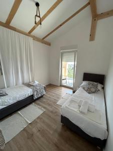 twee bedden in een kamer met witte muren en houten vloeren bij TwENty-Punat Apartments in Punat