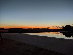 una piscina con una puesta de sol en el fondo en Country House Art and Garden en Monte Antico