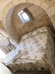 a bed in a stone room with a window at TRULLI LE 2 NICCHIE in Locorotondo