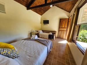 a bedroom with two beds and a tv in a room at Hotel Fazenda Santo Antônio in Vassouras