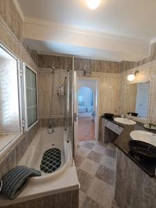 uma casa de banho com uma banheira, 2 lavatórios e um chuveiro em Lovely new House - Guests Apartments em Olhão