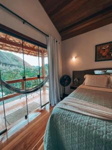 a bedroom with a bed and a large window at Chalés Vale das Pedras in Venda Nova do Imigrante