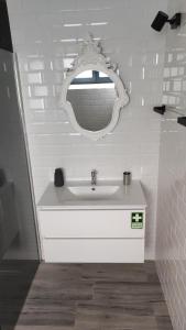 uma casa de banho com um lavatório branco e um espelho. em Costa do Moinho em Horta