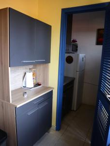 a kitchen with blue cabinets and a white refrigerator at Studio vue mer Le Colibri in Sainte-Anne