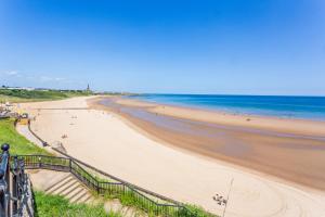 a beach with people on it and the ocean at The Priory House in Tynemouth