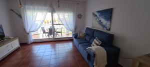 d'un salon avec un canapé bleu et d'un balcon. dans l'établissement Siente el relax., à Alcossebre