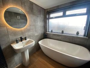 a bathroom with a tub and a sink and a mirror at Bluebell Cottage Heritage Town nr Brecon Beacons with hot tub in Blaenavon