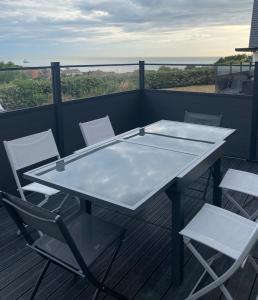 einen Tisch und Stühle auf einem Balkon mit Meerblick in der Unterkunft Parenthèse à la mer in Équihen-Plage