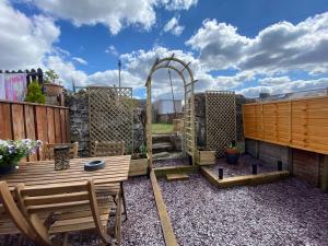 a patio with a wooden bench and a swing at Bluebell Cottage Heritage Town nr Brecon Beacons with hot tub in Blaenavon