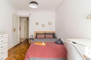 a white bedroom with a bed with a red blanket at Moderno apartamento en pleno centro in Santander