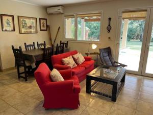 a living room with a red couch and a table at chacras del paraíso. in Tandil