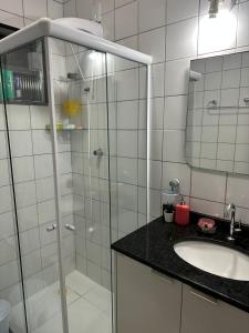 a bathroom with a shower and a sink and a mirror at Quarto particular na praia do flamengo in Salvador