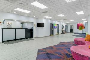 a large room with pink furniture and a tv at Quality Inn & Suites Banquet Center in Livonia