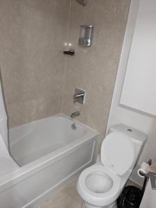a bathroom with a white toilet and a tub and a sink at ICE Condominiums in Toronto