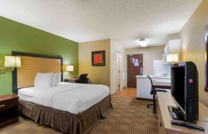 a hotel room with a bed and a desk with a television at Extended Stay America Suites - Kansas City - Overland Park - Quivira Rd in Lenexa