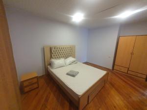 1 dormitorio pequeño con 1 cama y suelo de madera en Grand Village, en İsmayıllı