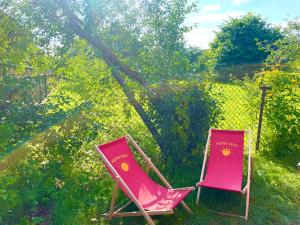 two pink lawn chairs sitting in the grass at CHATA OTWARTYCH OKIENNIC Pokoje Gościnne in Supraśl