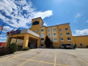 un edificio amarillo con banderas en un estacionamiento en Highland Suites Extended Stay, en Minot