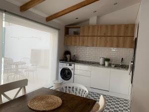 a kitchen with white cabinets and a table and chairs at Casa do Bairro in Seia