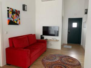 a living room with a red couch and a tv at Casa do Bairro in Seia