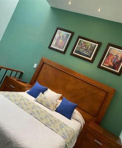 a bedroom with a bed with blue walls and pictures at Casa La Vikina in Guanajuato