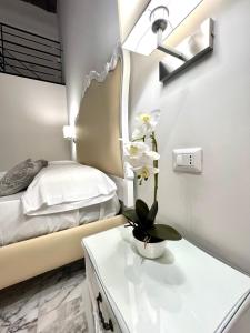 una camera da letto con un letto e un tavolo con un fiore sopra di MILUAR Luxury B&B - Vanvitelli a Napoli