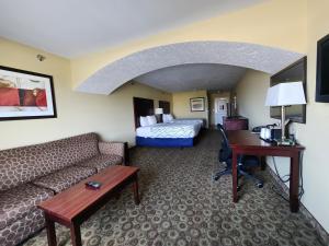 Habitación de hotel con sofá, cama y escritorio. en Highland Suites Extended Stay, en Minot
