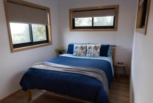 a bedroom with a blue bed with two windows at Burnie Unit - The Cape in Burnie