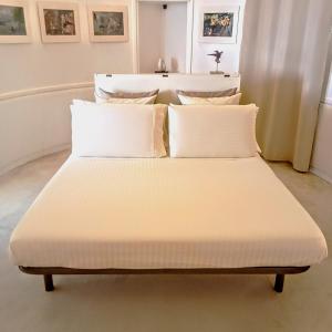 Bett mit weißer Bettwäsche und Kissen in einem Zimmer in der Unterkunft Attico d'arte sulla Valle dei Templi in Agrigento