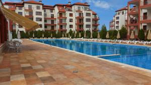 a swimming pool in a hotel with tables and chairs at COCO Family Vacation in Aheloy