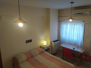 - une chambre avec un lit et une table avec un bureau dans l'établissement Center Studio Apartamento en el centro de Trelew, à Trelew