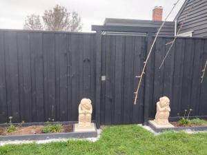 two stone statues in a yard next to a fence at Zen Out on Surrey in Alfredton