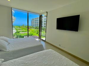 a bedroom with two beds and a flat screen tv at Espectacular frente al Mar- Morros Zoe - Playa Manzanillo Cartagena in Cartagena de Indias
