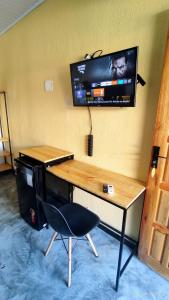 a desk with a chair and a television on a wall at Pousada Siriba in Caravellas