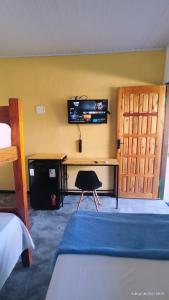 a bedroom with a desk and a tv on the wall at Pousada Siriba in Caravellas