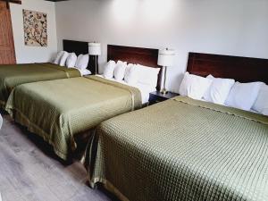 Habitación de hotel con 2 camas y mantas verdes en Dunes Motel - Bend, en Bend