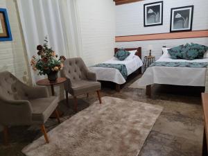a room with two beds and two chairs and a table at Pousada Recanto João de Barro in Cunha