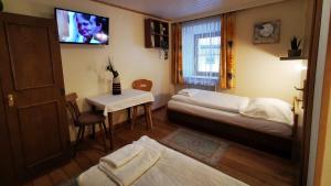 a bedroom with two beds and a table and a tv at Gasthof Geronimo in Weissbach bei Lofer