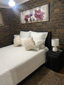 a bedroom with a bed with a brick wall at We Love Properties Guest House in Centurion