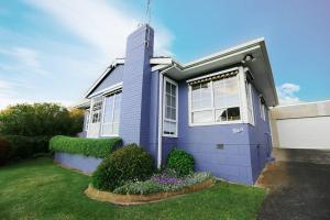 a blue house with a grass yard in front of it at Bluey in Warrnambool