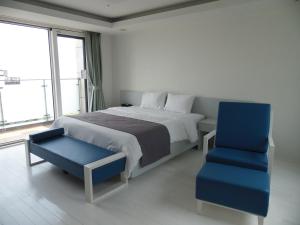 um quarto com uma cama e uma cadeira azul em Healthcare Town Resort em Seogwipo