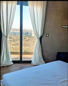 sypialnia z łóżkiem i dużym oknem w obiekcie Villa piscine sans vis à vis vue mer w mieście Tanger