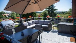 patio z kanapą, stołami i parasolem w obiekcie Le toit des Fagnes w mieście Jalhay