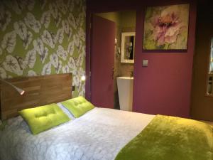 a bedroom with a bed with a green pillow on it at Hôtel du Commerce in Montauban