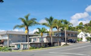 a building with palm trees in front of a street at Bayview Motel in Paihia