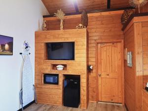 Habitación con pared de madera, TV y puerta. en Dunes Motel - Bend, en Bend