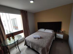 a bedroom with a bed with a glass table and a window at Inti Llaqta Hotel & Suites in Lima