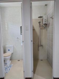 La salle de bains blanche est pourvue d'une douche et de toilettes. dans l'établissement DULLI TRANSIENT HOUSE, à Lipa
