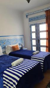 - une chambre avec 3 lits à rayures bleues et blanches dans l'établissement Casa Familia, à Chefchaouen