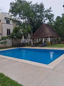 Departamento Ciudad MayaKoba 2 habitaciones في بلايا ديل كارمن: حمام سباحة مع شرفة بجوار منزل